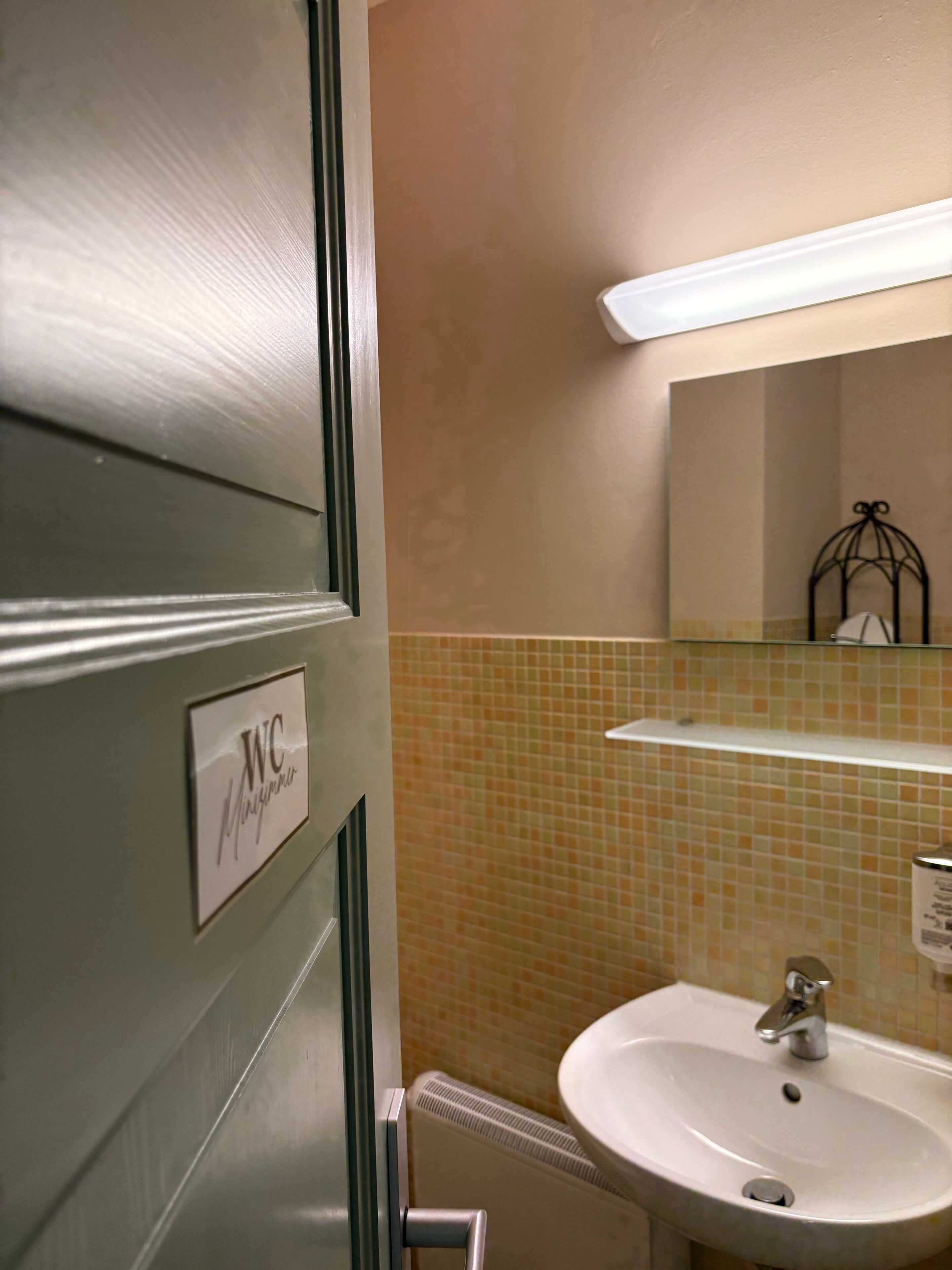Un baño con letrero de inodoro, un lavamanos y un salpicadero de azulejos.