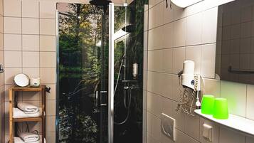 Un baño moderno con ducha envuelta en vidrio, inodoro, lavabo y estante de madera con toallas.