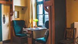 A cozy room with a desk, two chairs, a lamp, and a radiator.
