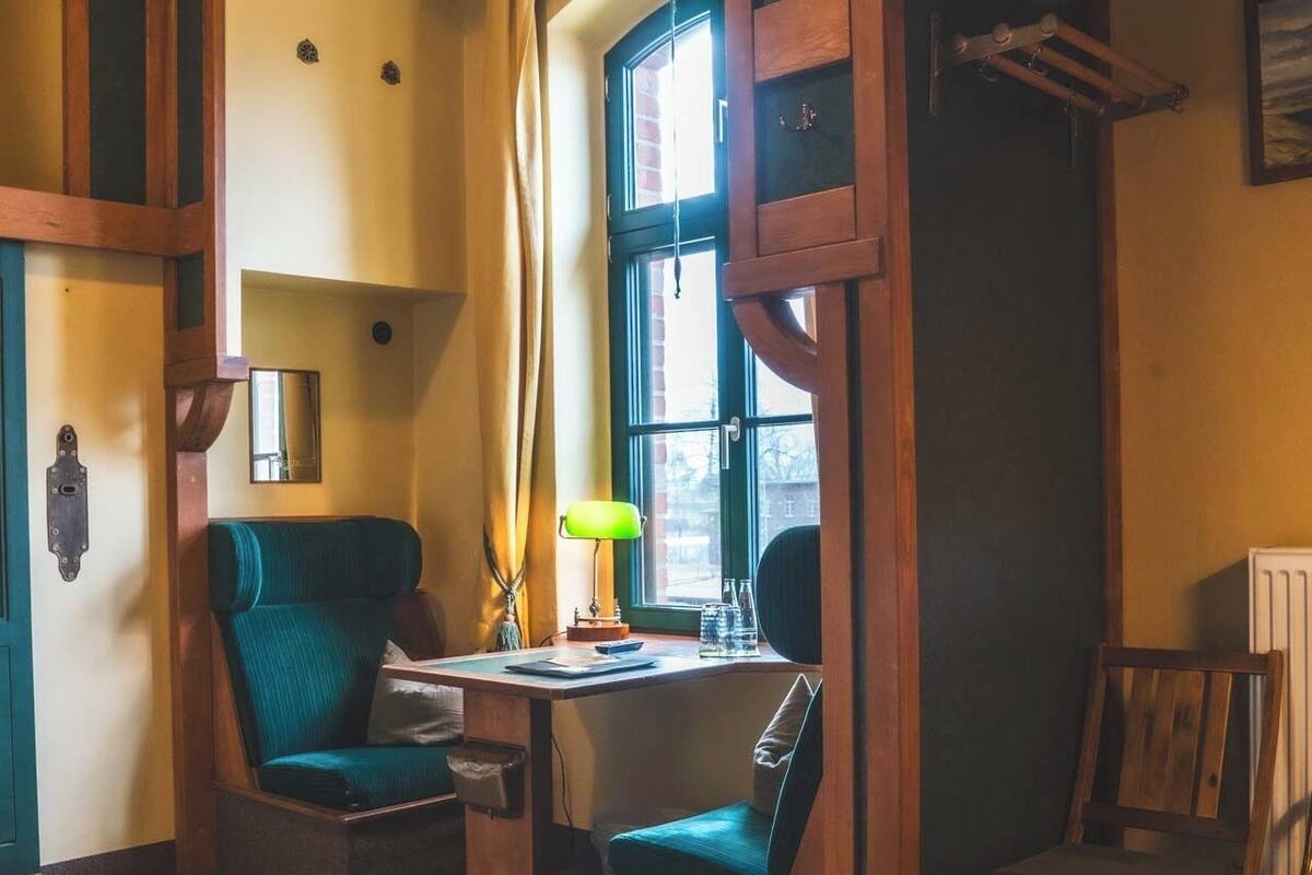 A cozy room with a desk, two chairs, a lamp, and a radiator.