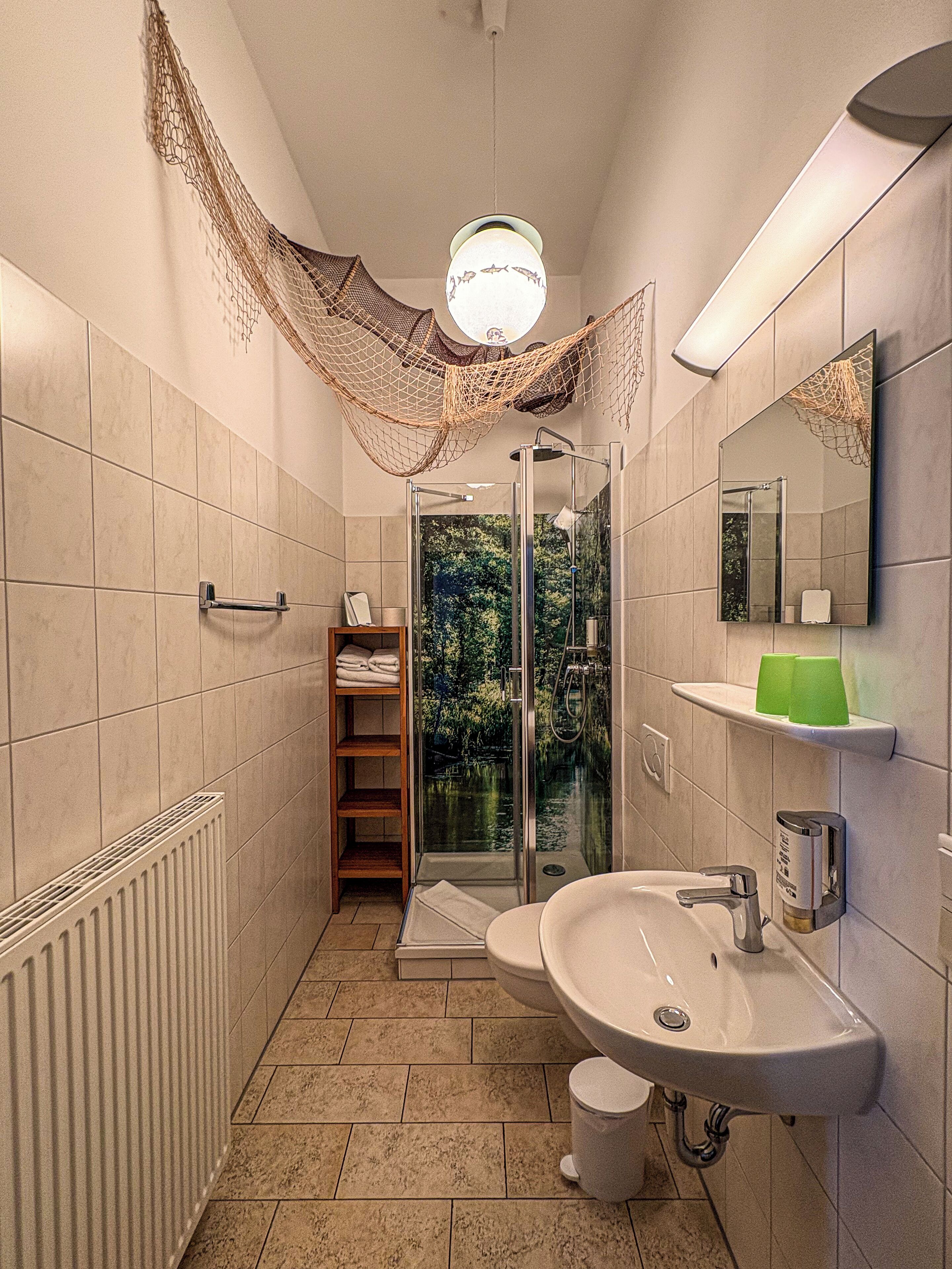 A bathroom with a glass-enclosed shower, a sink, a toilet, and a towel rack.