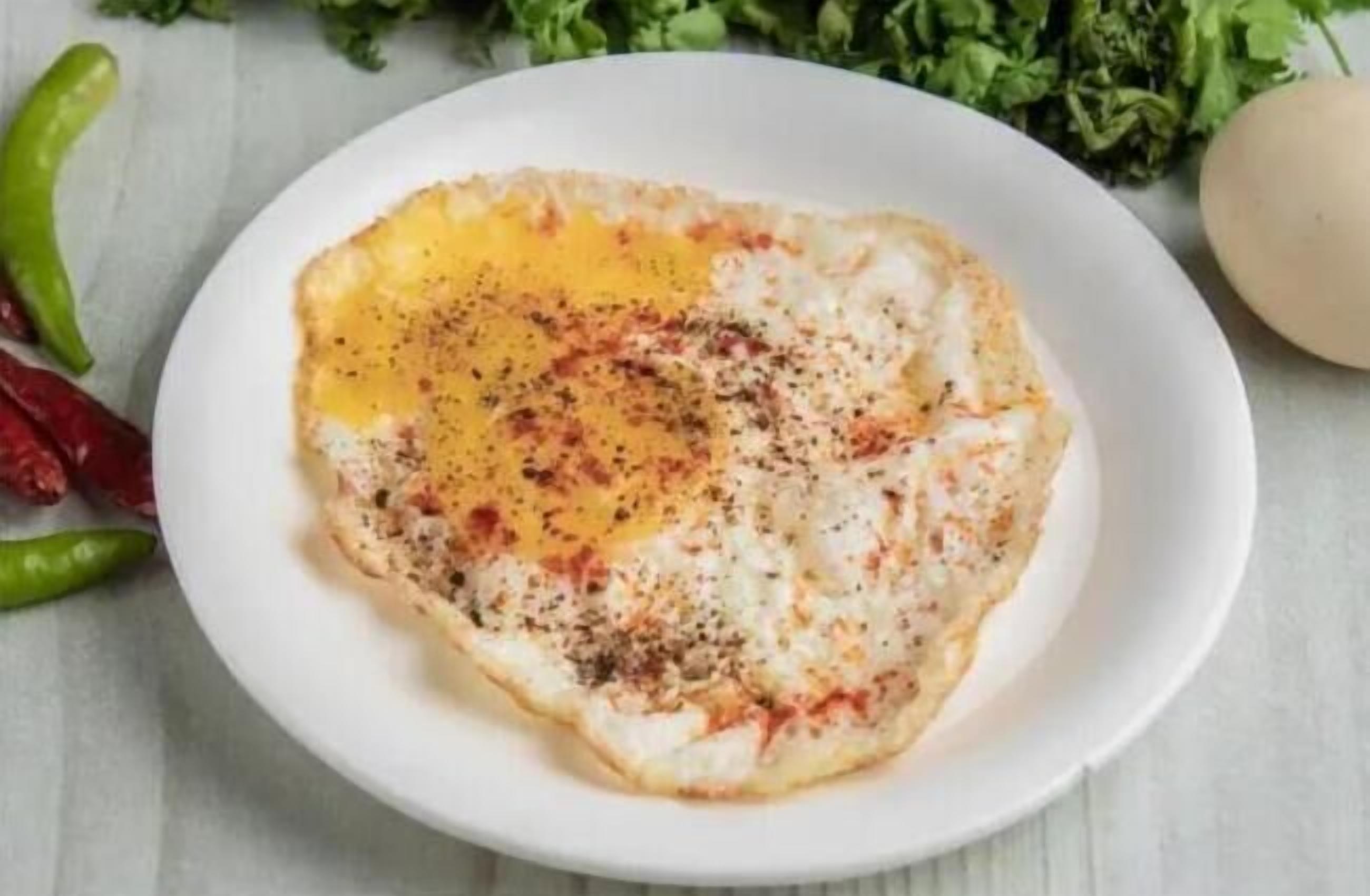 A plate with a fried egg, black pepper, and red chili flakes.
