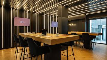 A modern conference room with a long table, black chairs, and two screens displaying the logo of the InterContinental Hotels Group.