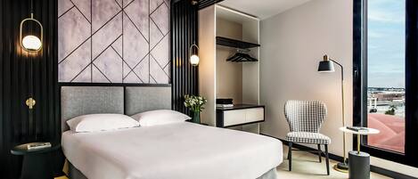 Une chambre moderne avec un grand lit, une chaise, un bureau et une vue sur la ville par une grande fenêtre.