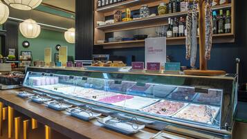 Un comptoir de charcuterie proposant une variété de viandes et de fromages, une étagère à vin au-dessus, et un panneau indiquant les produits de charcuterie.