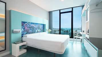 Ein modernes Hotelzimmer mit einem großen Bett, einem Schreibtisch und Blick auf die Stadt.