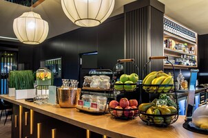 A bar area with a variety of fruits, a selection of bottles, and a wine rack.