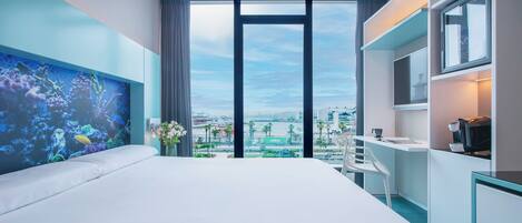 Habitación de hotel moderna con una cama grande, un escritorio y vistas a la ciudad a través de amplias ventanas.