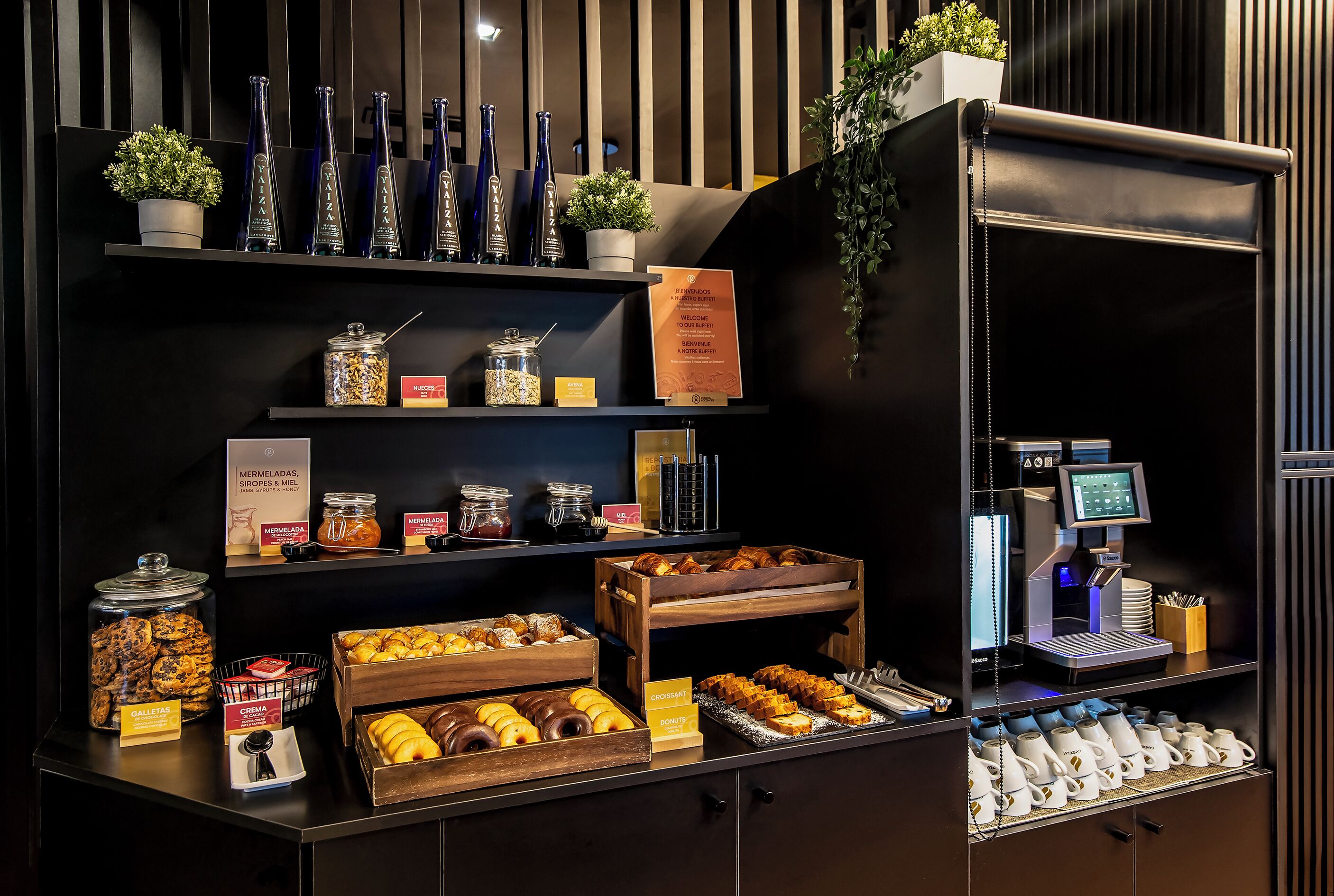 Una estación de café con diversas pastas, una máquina de café y un quiosco de autoservicio.