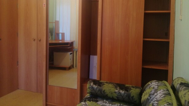 Une pièce avec une armoire en bois, un miroir et un canapé à motifs floraux.
