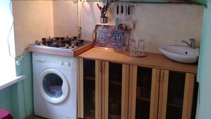 Une cuisine de taille réduite, équipée d’un lave-linge, de meubles en bois et d’un évier.