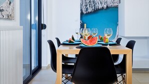 A dining area with a table set for four, a large window, and a painting on the wall. - Seametry Villa (Νεροκουρος)