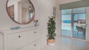 Un baño moderno con un espejo grande, muebles blancos, una planta en maceta y vistas a una piscina.