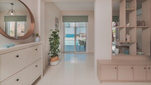 Un interior moderno con un espejo grande, una planta en maceta, un comedor con vistas y un mueble de estanterías empotrado.
