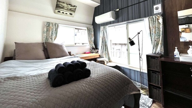 Ett hotellrum med en säng, ett skrivbord, en spegel och ett fönster med gardiner.
