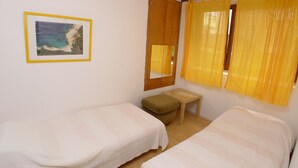 A room with two single beds, a small table, a mirror, and a framed picture on the wall. - Apartment for 5 Persons With two Bedrooms and Internet (Medulin)