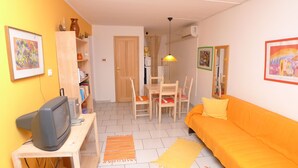 A compact living space with a sofa, television, dining table, chairs, and a kitchen area. - Apartment for 5 Persons With two Bedrooms and Internet (Medulin)