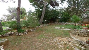 A garden with a stone pathway, various plants, and trees. - Apartment for 5 Persons With two Bedrooms and Internet (Medulin)
