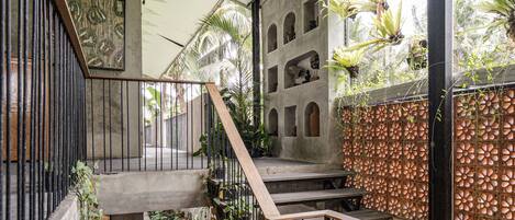 A multi-level interior with concrete walls, metal railings, and potted plants.