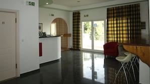 A reception area with a counter, a red chair, and a door.