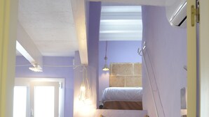 A room with a wooden ladder, a red sofa, a window with blinds, and a light fixture. - Rifugio Azul (Ciutadella de Menorca)