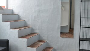 A staircase with white walls and red-tiled flooring leading to a landing. - Rifugio Azul (Ciutadella de Menorca)