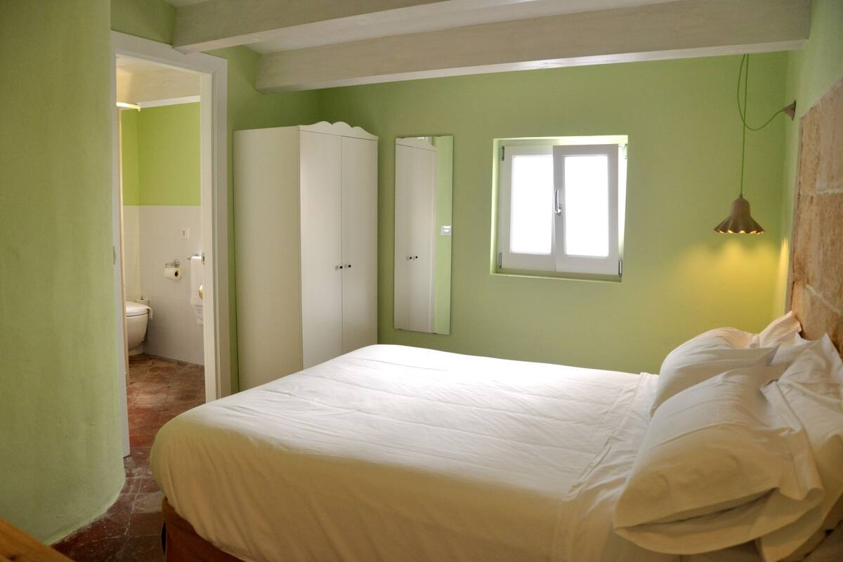 A bedroom with a bed, a wardrobe, a mirror, and a window.
