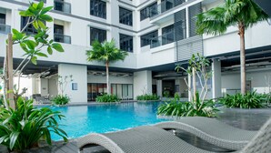 A modern indoor pool area with a clear view of the pool, lounge chairs, and surrounding greenery. - Ezzyhome Medini (Iskandar Puteri)