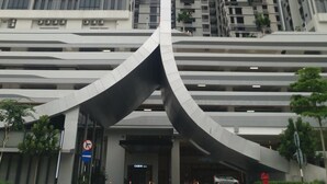 A modern building with a curved entrance and multiple high-rise buildings in the background. - Ezzyhome Medini (Iskandar Puteri)