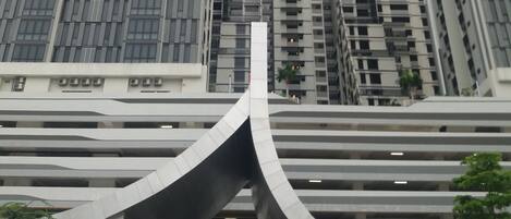 Een modern gebouw met een gebogen entree en meerdere hoge gebouwen op de achtergrond.