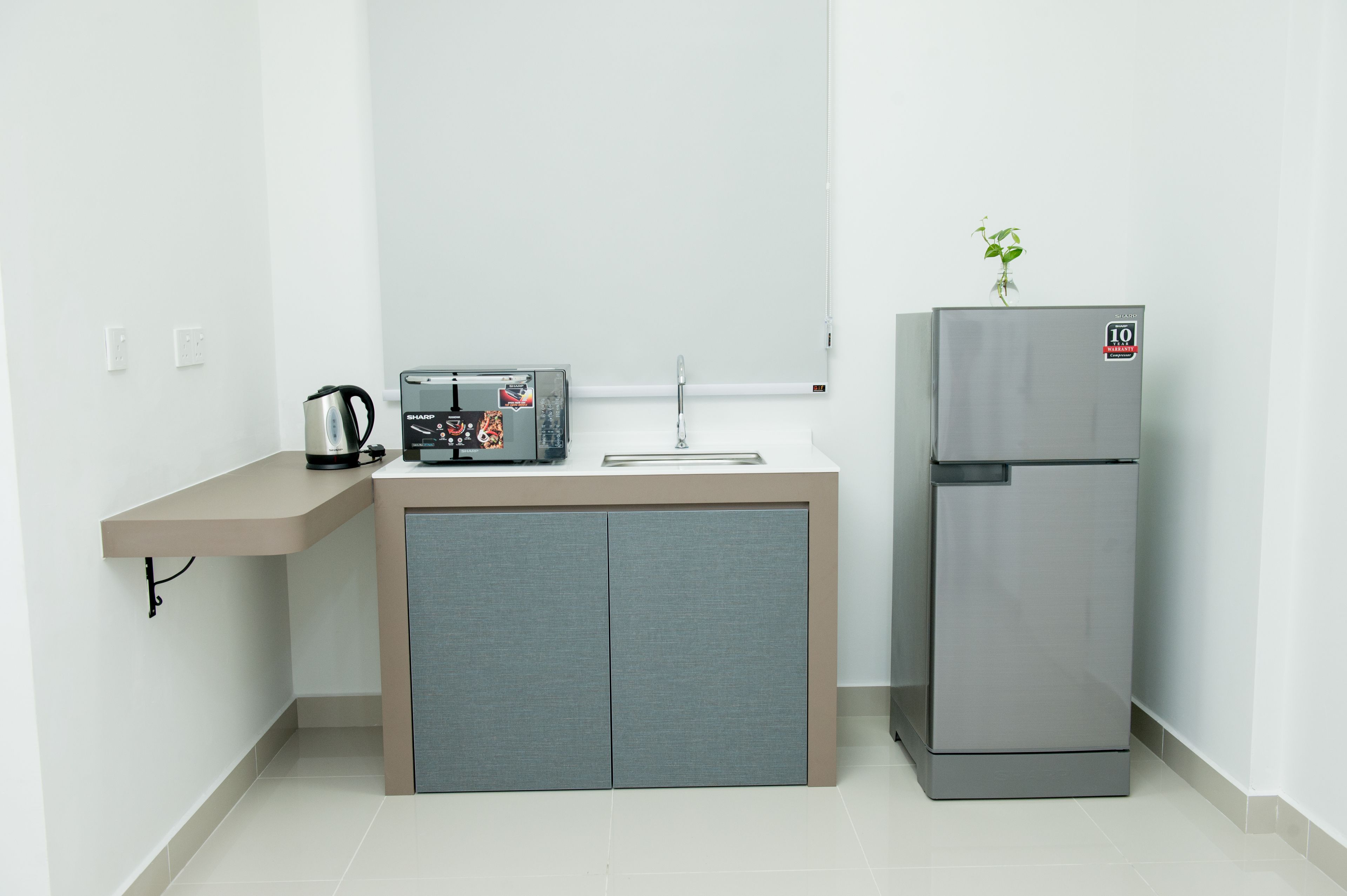 A compact kitchen with a built-in sink, a coffee maker, and a refrigerator.