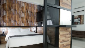 A modern bedroom with a wooden wall panel, a large bed, a nightstand, and a bench. - Ezzyhome Medini (Iskandar Puteri)