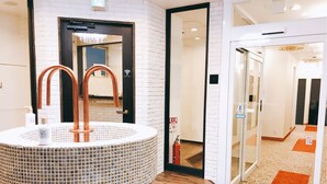 Ein modernes Badezimmer mit einem großzügigen Waschbecken aus Mosaikfliesen, Holzhandtuchhaltern und einem Spiegel darüber.