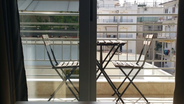 A room with a view of a balcony, a puzzle on the table, and a striped mat. - Cozy Flat near Athens City Center (Athens)