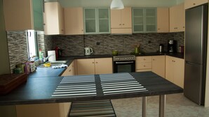 A modern kitchen with striped mats on the island, a stainless steel refrigerator, and a coffee maker. - Cozy Flat near Athens City Center (Athens)