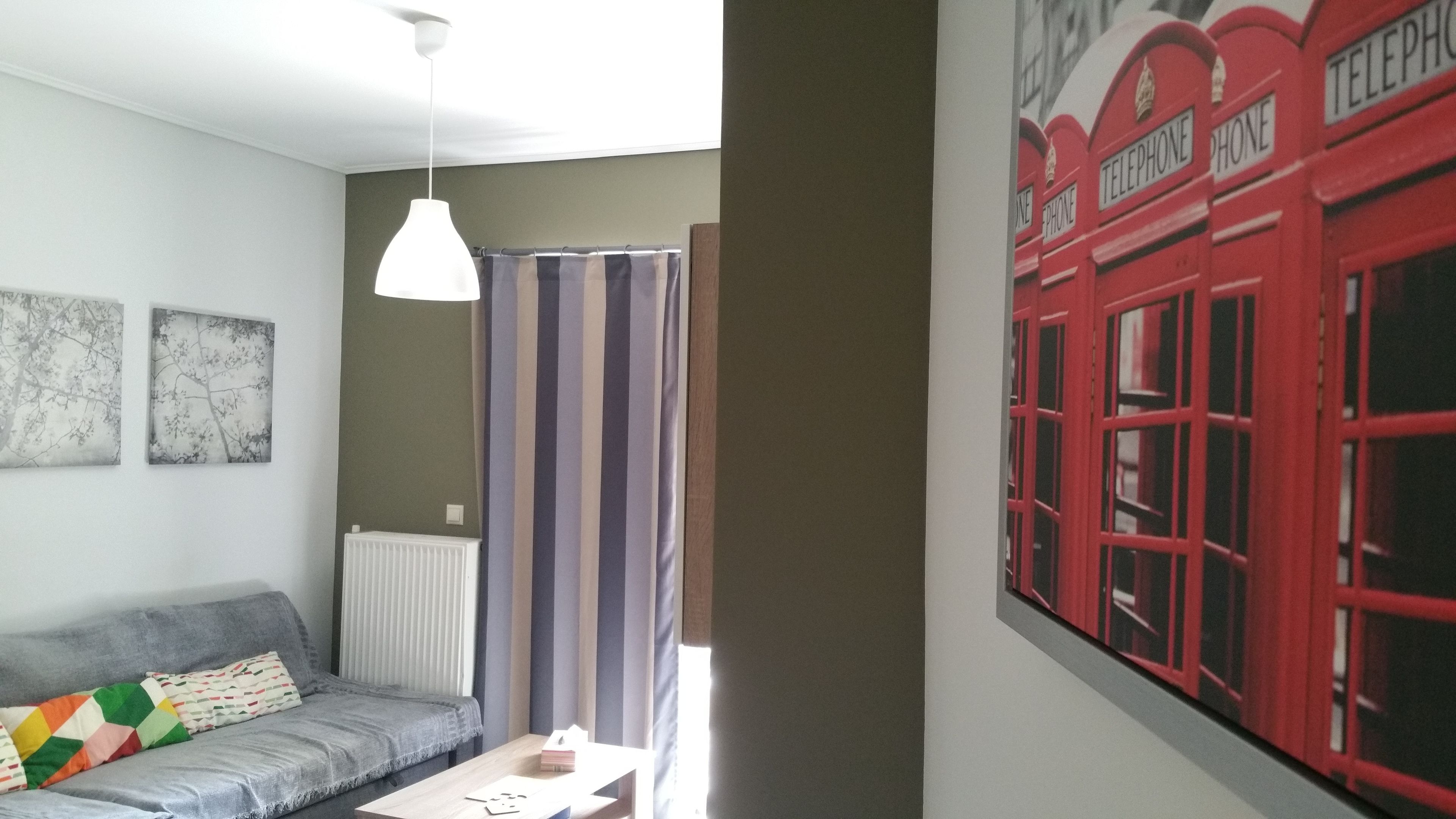 A living room with a grey sofa, a white pendant light, and a wall-mounted radiator.