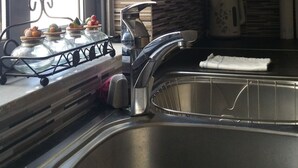 A kitchen with a gas stove, stainless steel sink, and a window with blinds. - Cozy Flat near Athens City Center (Athens)