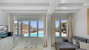 Un salon moderne doté d’une grande fenêtre donnant sur une piscine et une plage.