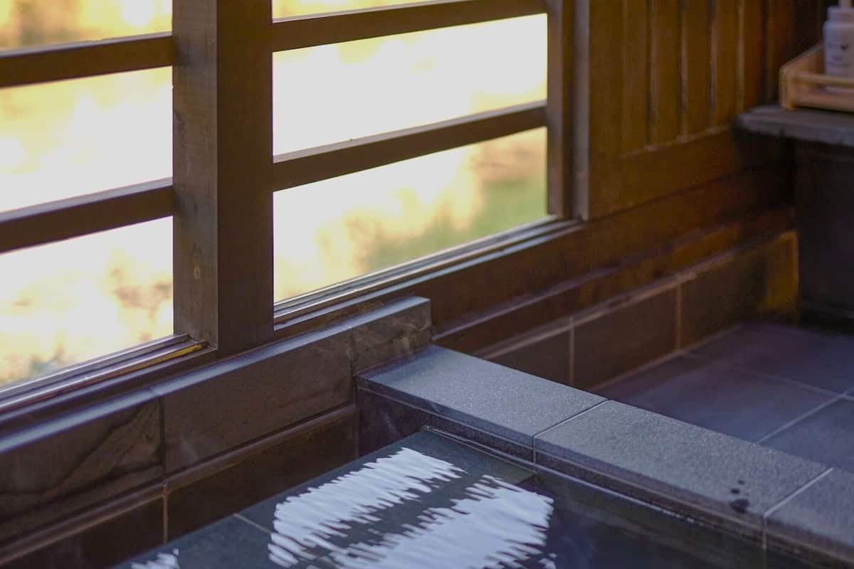 A window with a view of trees, a tiled floor, and a glass partition.