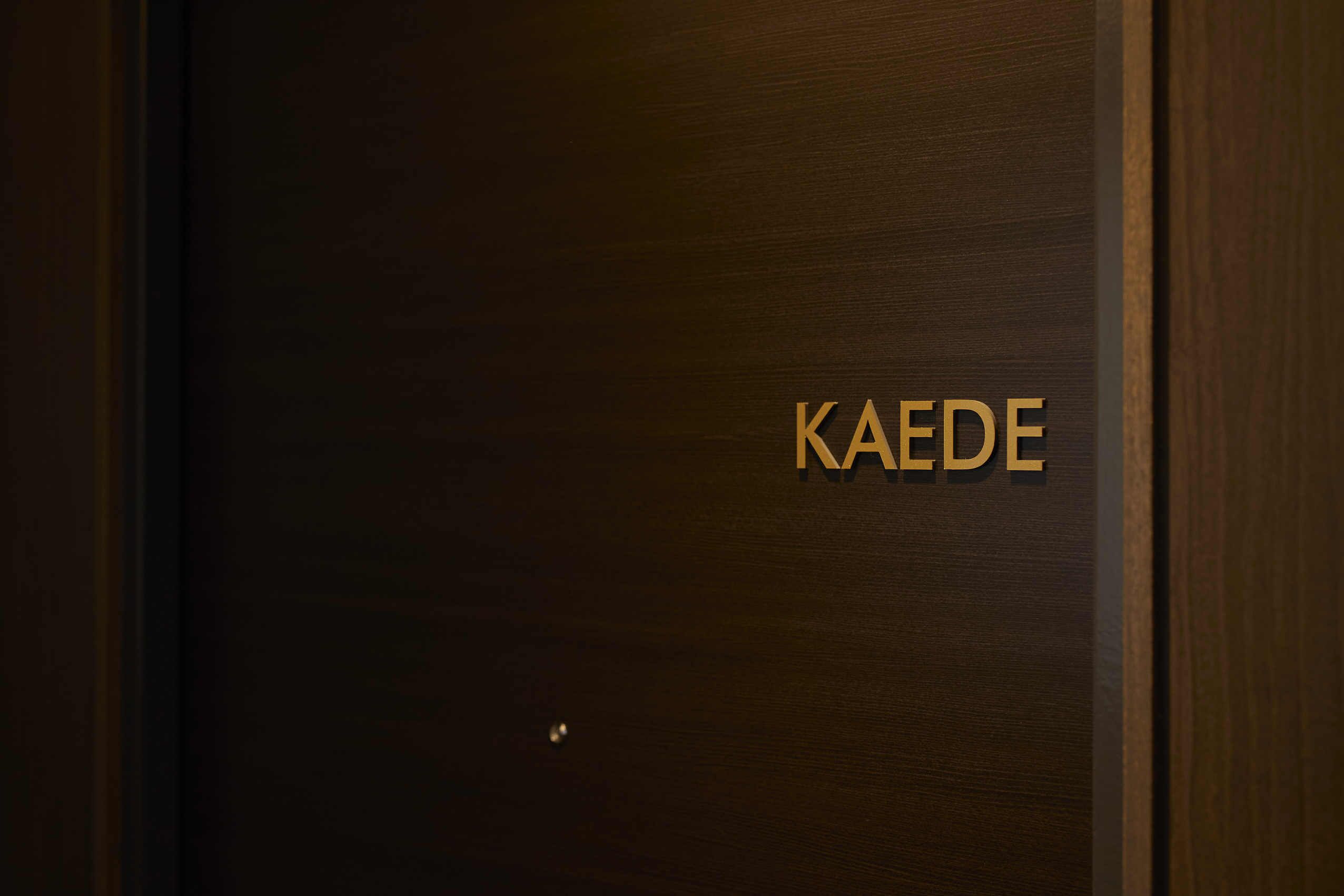 Eine Holztür mit dem Namen 'KAEDEN' in goldener Schrift.