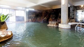 A hot spring bath with stone walls, a central column, and a seating area. - Myoken Onsen Nemu (Kirishima)