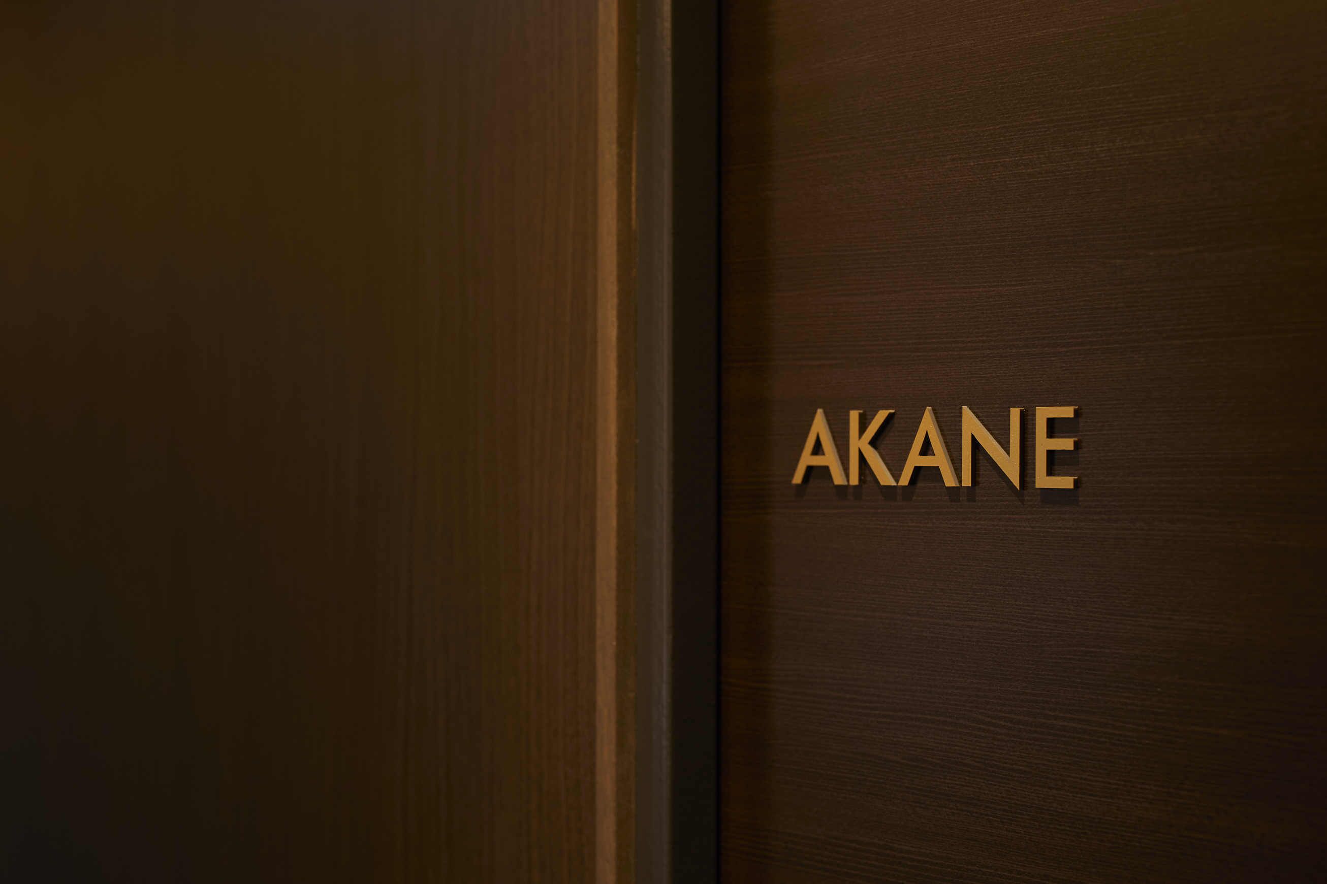 Eine Holztür mit der Aufschrift 'AKANE' in goldener Schrift.