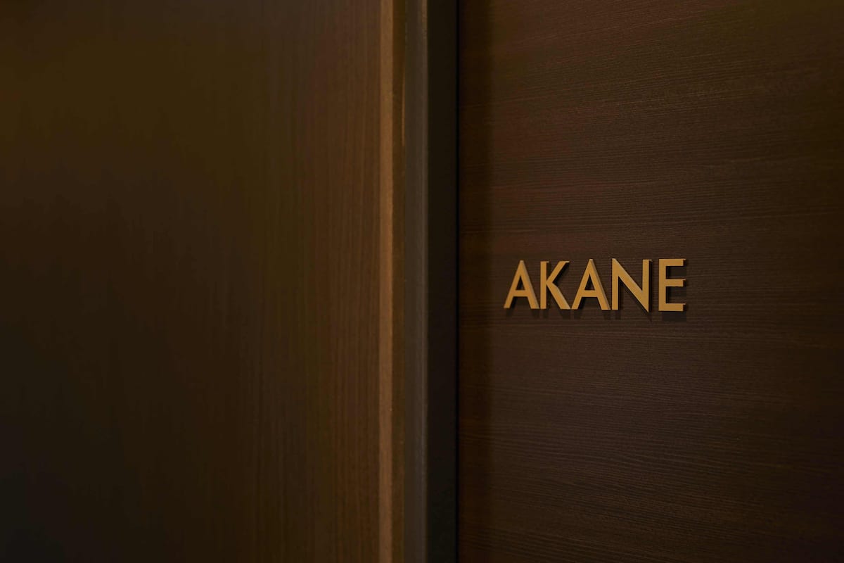 Een houten deur met de naam 'AKANE' in gouden letters.