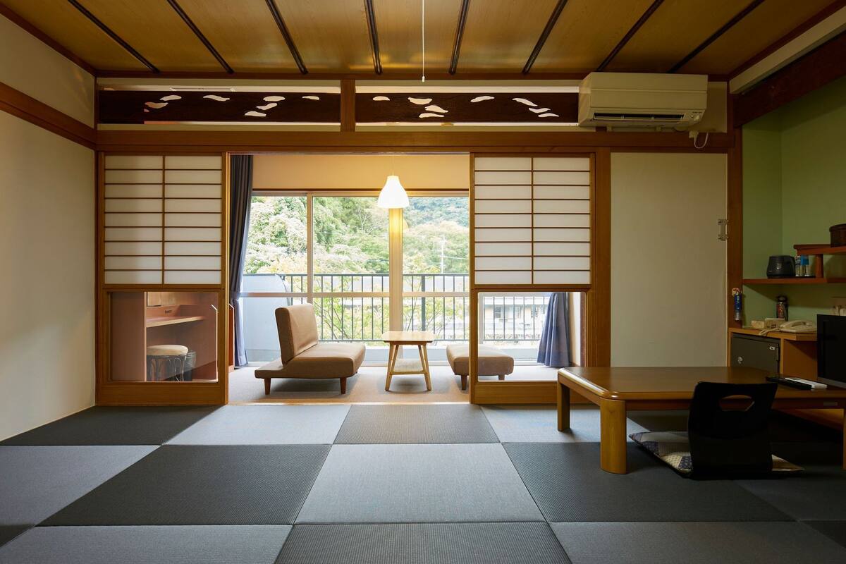 Een traditionele Japanse kamer met tatami vloeren, een schuifdeur, een bank, een tafel en een lamp.