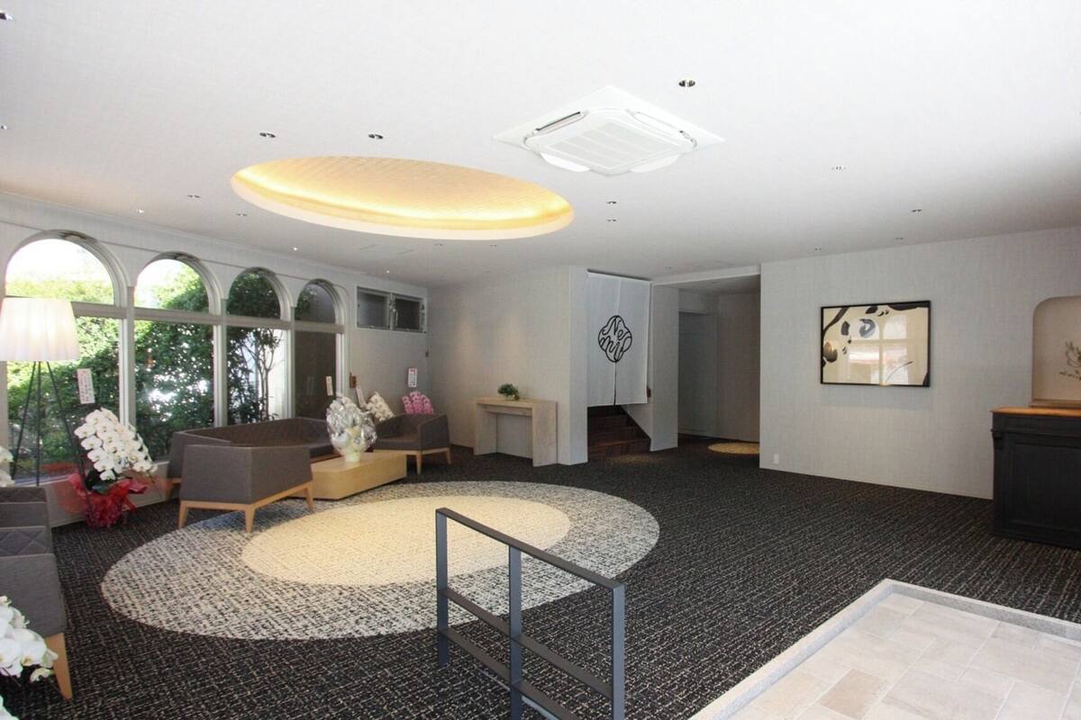 A spacious lobby with a central seating area, a reception desk, and a staircase leading to upper floors.