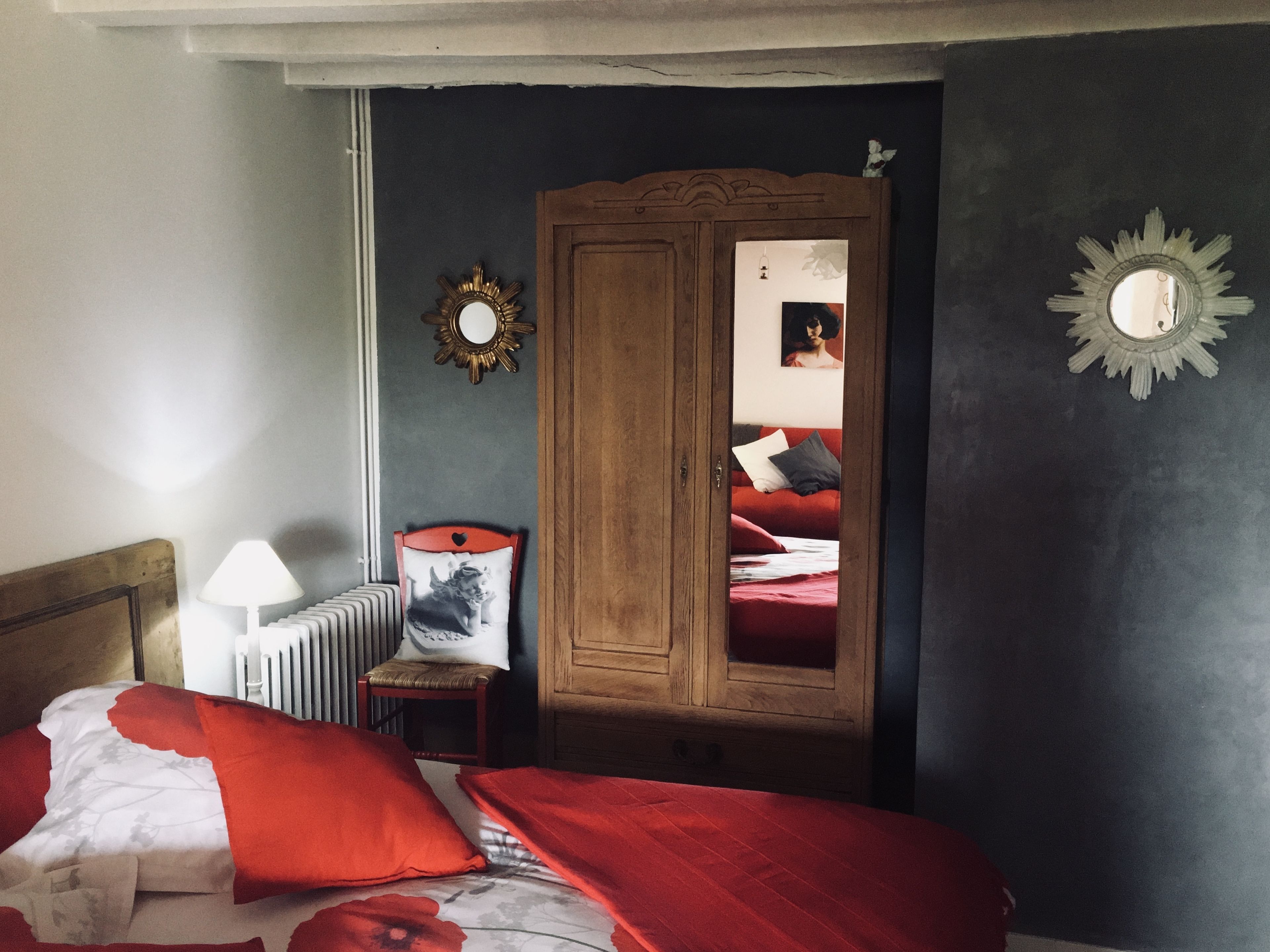 Um quarto com uma cama, um guarda-roupa de madeira, um radiador e um espelho na parede.