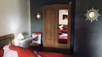 Um quarto com uma cama, um guarda-roupa de madeira, um radiador e um espelho na parede.