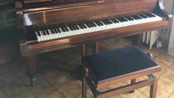 Un pianoforte a coda con una panca in una stanza con pavimento piastrellato.