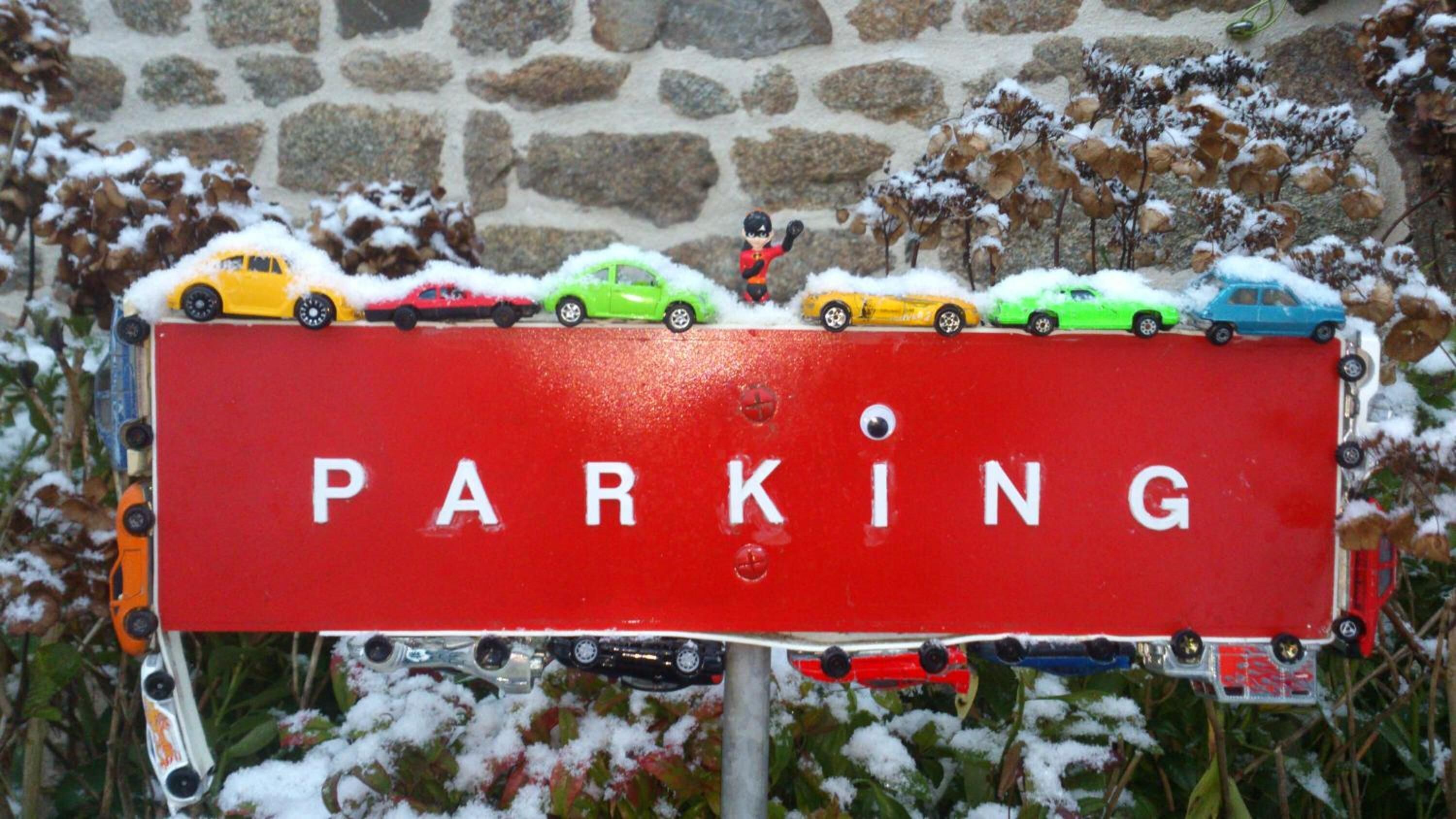 Un panneau de signalisation rouge indiquant un espace de stationnement, avec le mot « PARKING » écrit en lettres blanches.
