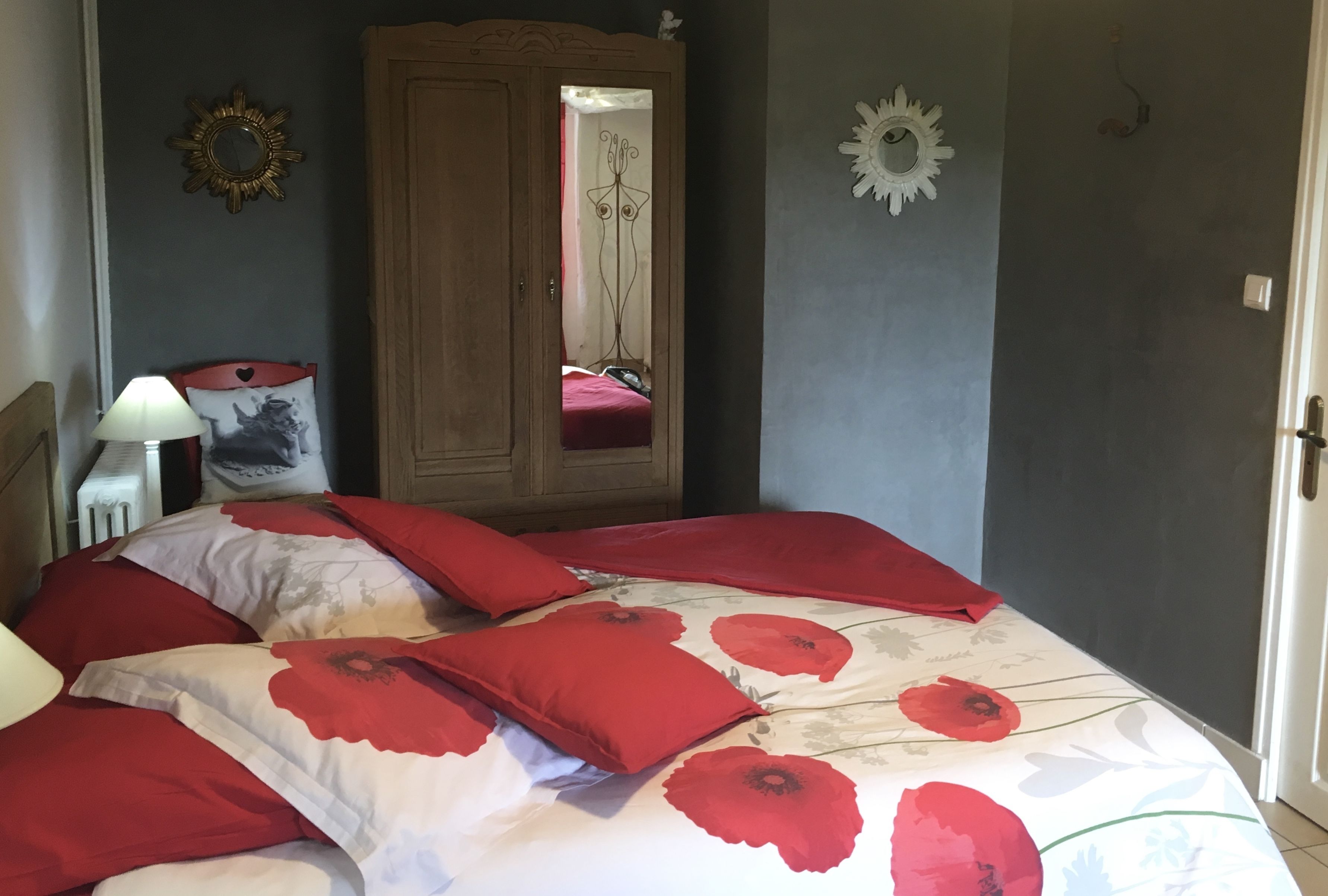 A bedroom with a bed, a wardrobe, a mirror, and wall decorations.